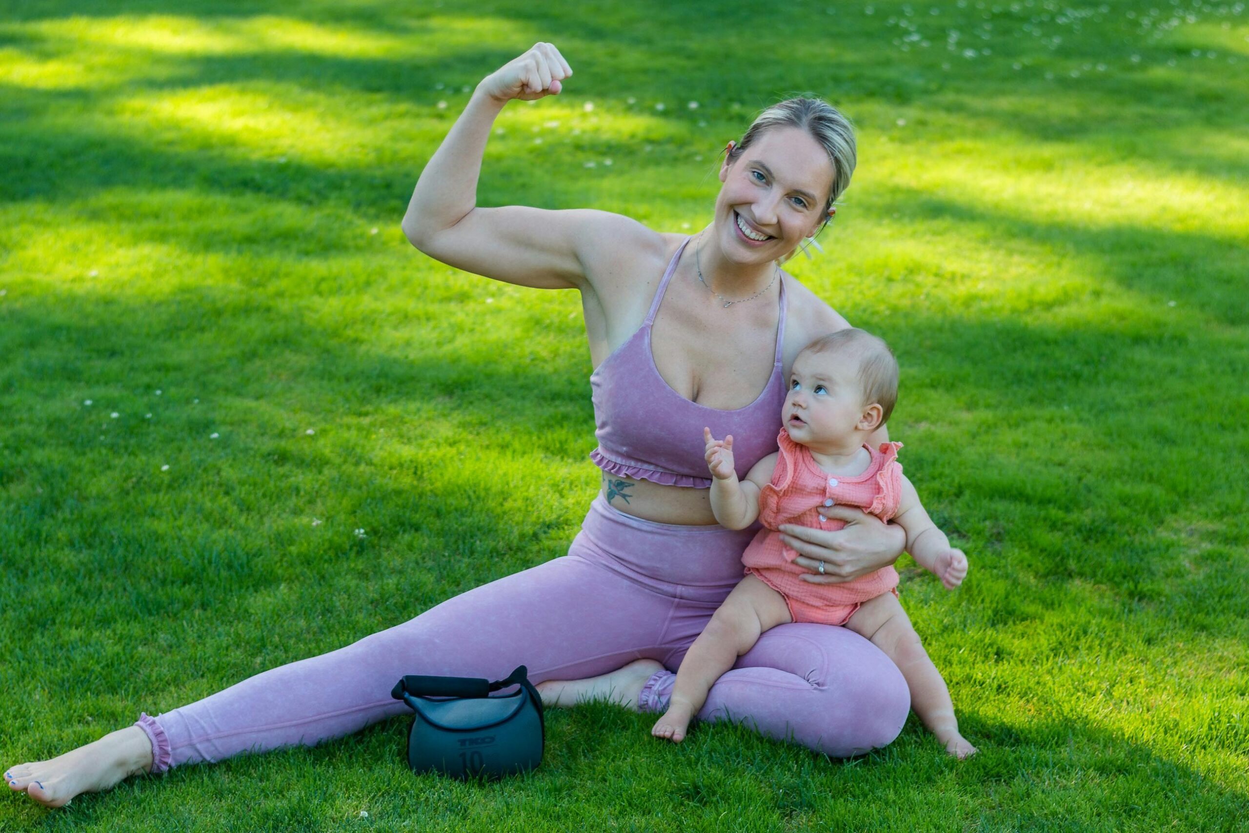Woman flexing her bicep with baby on her lap